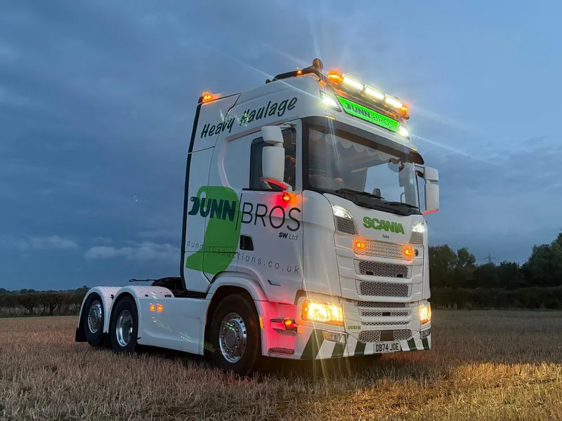 Dunn Bros Scania heavy haulage unit with its lights on at dusk